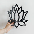 A black wooden wall shelf shaped like a lotus flower, mounted in the corner of a room. The shelf holds a candle in a glass holder, several crystal stones, and a small spray bottle. Decorative and compact, it adds a serene, spiritual touch to the space. Dimensions are 23cm (9.05in) wide and 29cm (11.41in) tall.