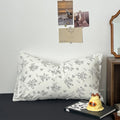 Creamy white bedding set printed with black outlined floral designs, giving a delicate and minimalist look. The bedding is soft and rumpled, styled with black pillows and cozy bedroom decor.