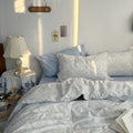White duvet cover set with light blue floral line art and matching pillowcases styled in a cozy vintage-inspired bedroom.