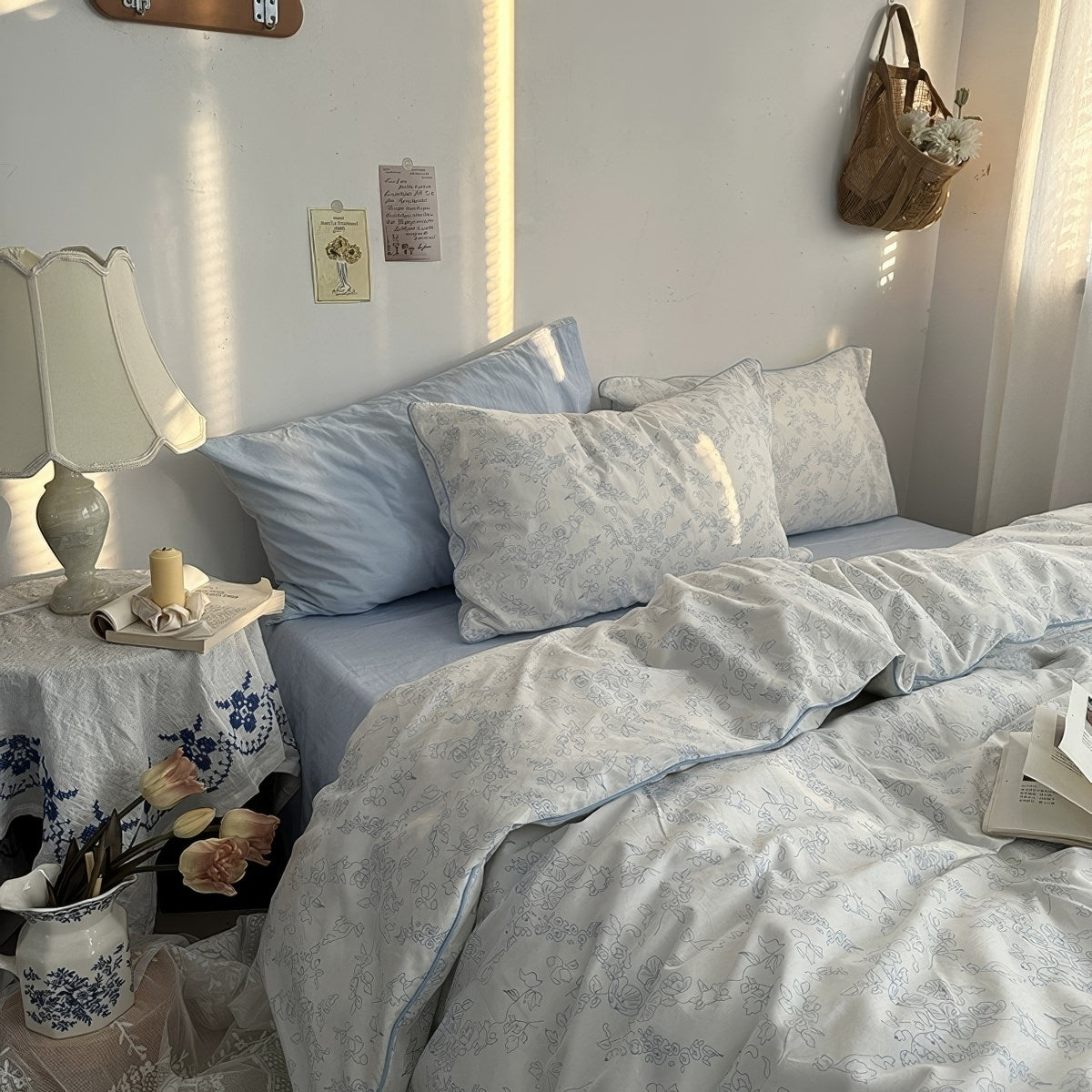 White duvet cover set with light blue floral line art and matching pillowcases styled in a cozy vintage-inspired bedroom.