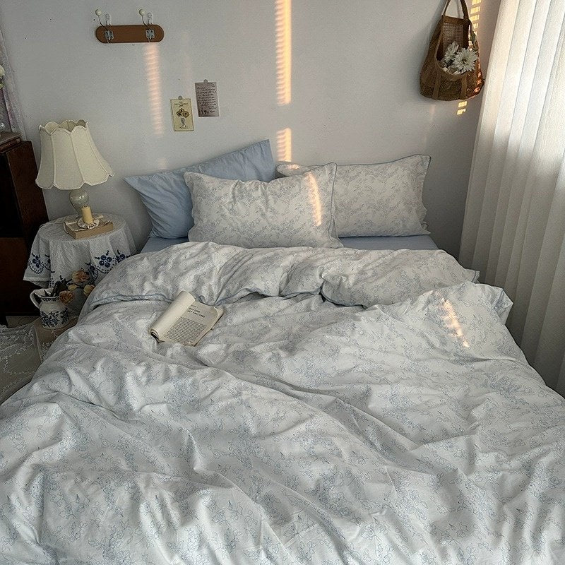 White duvet cover set with light blue floral line art and matching pillowcases styled in a cozy vintage-inspired bedroom.