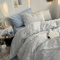 White duvet cover set with light blue floral line art and matching pillowcases styled in a cozy vintage-inspired bedroom