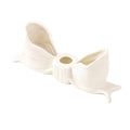 Ceramic bow-shaped candle holder in pink, red, and white with a glossy finish, designed to hold taper candles; decorative and elegant for home decor.