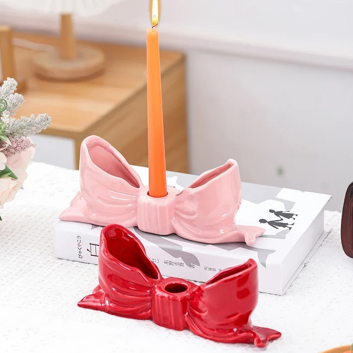 Ceramic bow-shaped candle holder in pink, red, and white with a glossy finish, designed to hold taper candles; decorative and elegant for home decor.