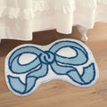 Blue and white bow-shaped rug on a wooden floor with a white curtain in the background.