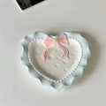 A pastel-colored, heart-shaped ceramic plate featuring scalloped edges, embossed hearts, and an elegant bow accent. Available in soft pink, pastel blue, and delicate yellow colors.