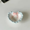 A pastel-colored, heart-shaped ceramic plate featuring scalloped edges, embossed hearts, and an elegant bow accent. Available in soft pink, pastel blue, and delicate yellow colors.