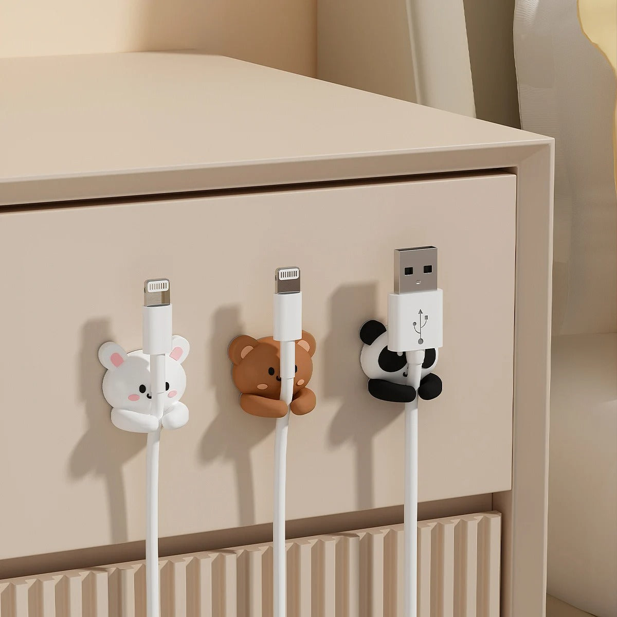 Set of two black-and-white kawaii panda cable organizer clips made of silicone, holding charging cables neatly