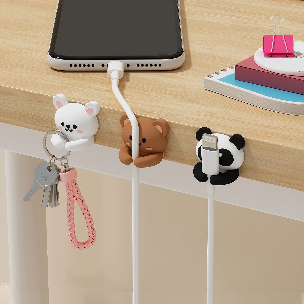 Set of two black-and-white kawaii panda cable organizer clips made of silicone, holding charging cables neatly