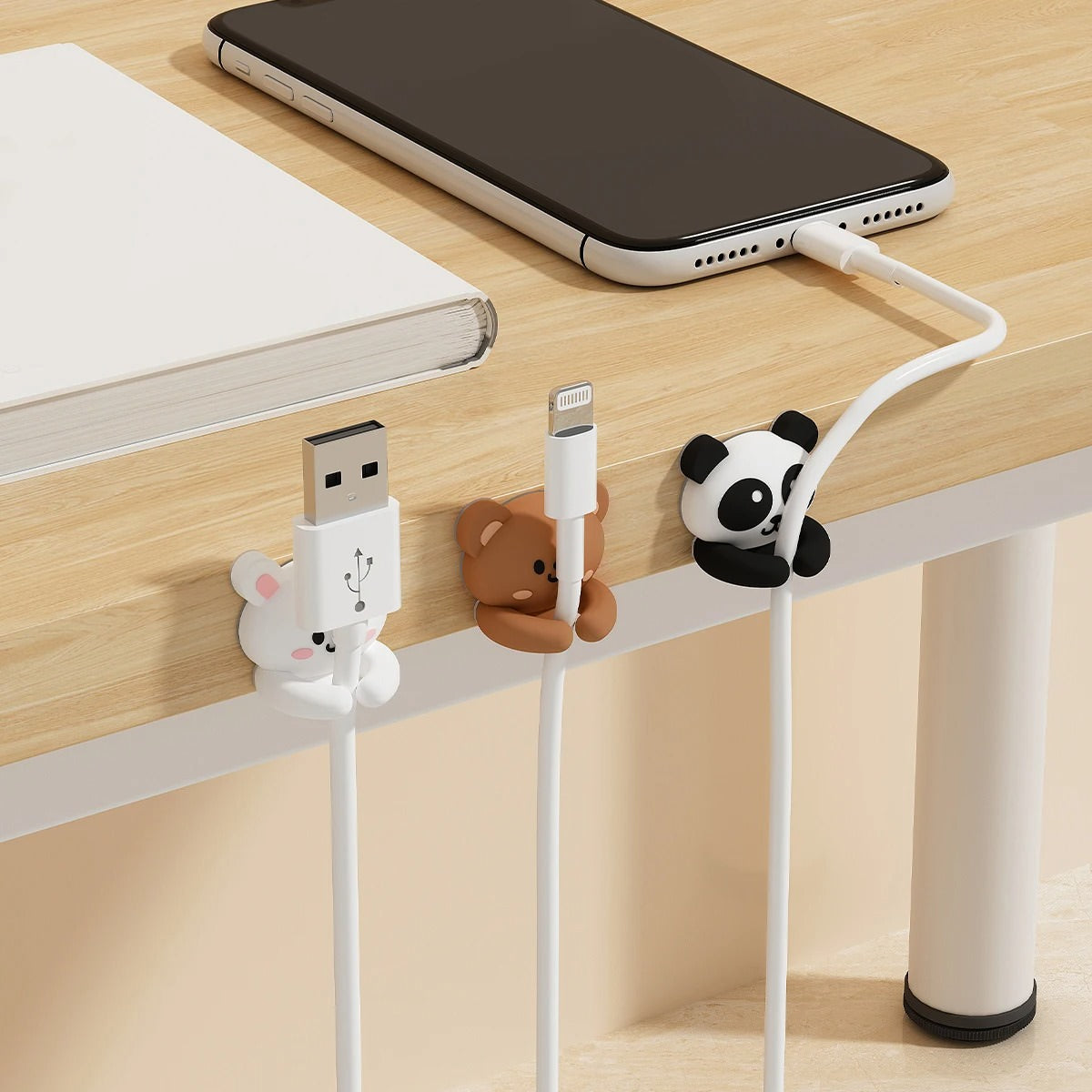 Set of two black-and-white kawaii panda cable organizer clips made of silicone, holding charging cables neatly