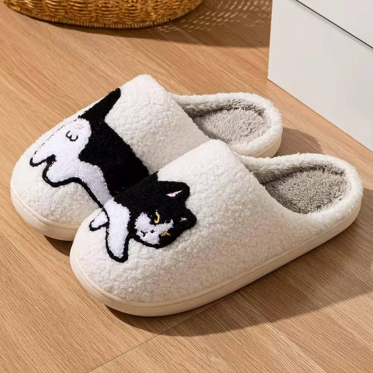 Pair of white plushie slippers with a black and white cat design