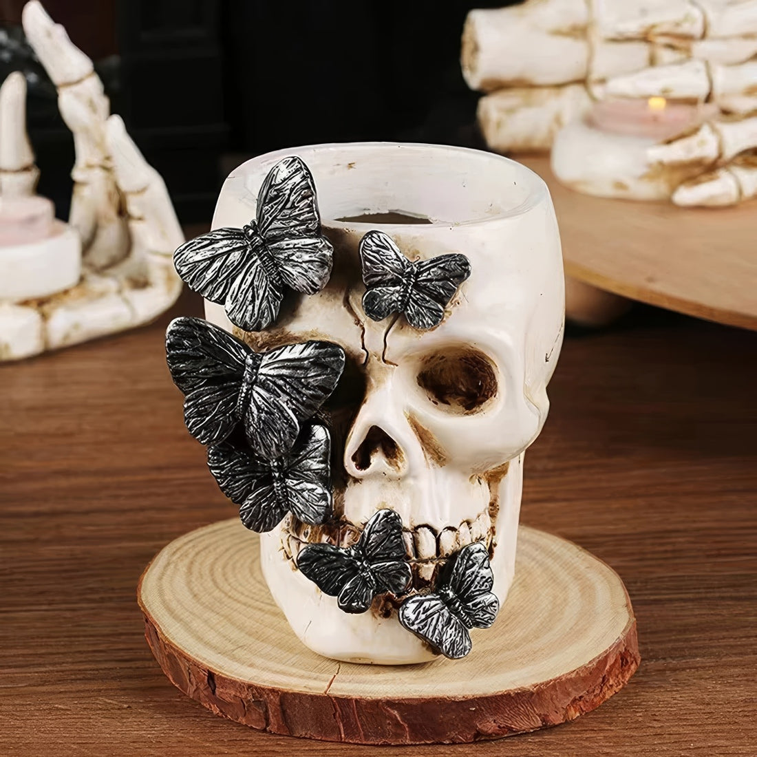 A resin brush holder designed as a skull decorated with detailed black butterflies. It measures 8cm wide and 10.3cm tall