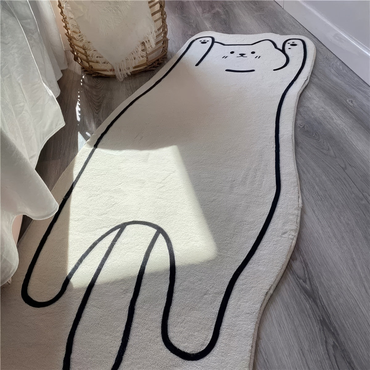 A soft, white floor mat shaped like a stretched-out cat with a simple black outline