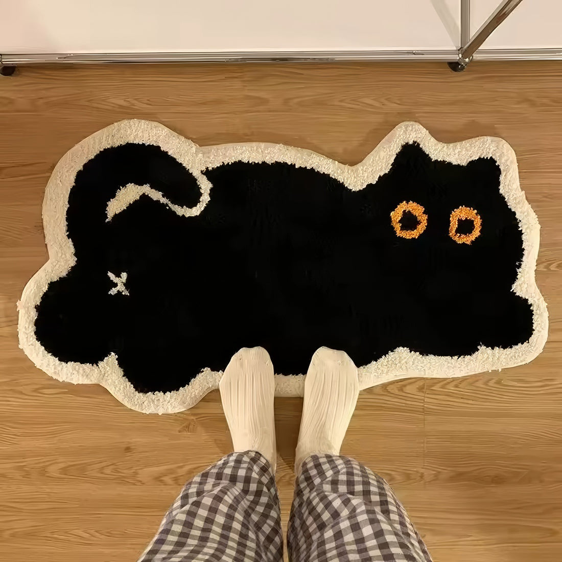 Black cat-shaped tufted rug with white border on a white background