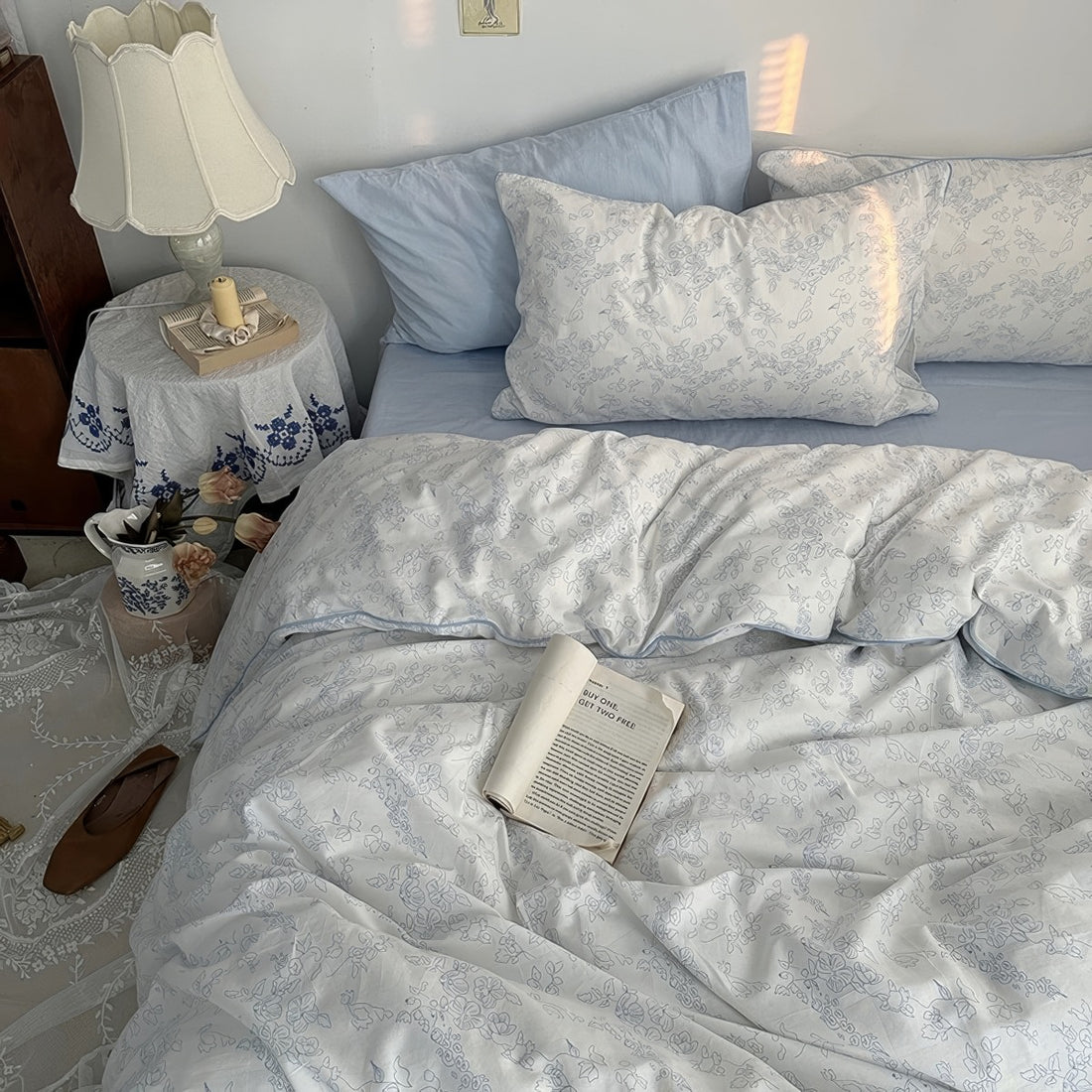 White duvet cover set with light blue floral line art and matching pillowcases styled in a cozy vintage-inspired bedroom