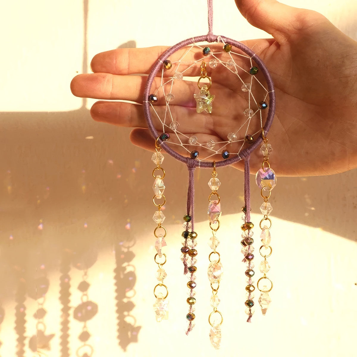 Crystal dreamcatcher wall hanging with prism beads, star charms, and sun-catching crystal strands in ivory and pink designs.