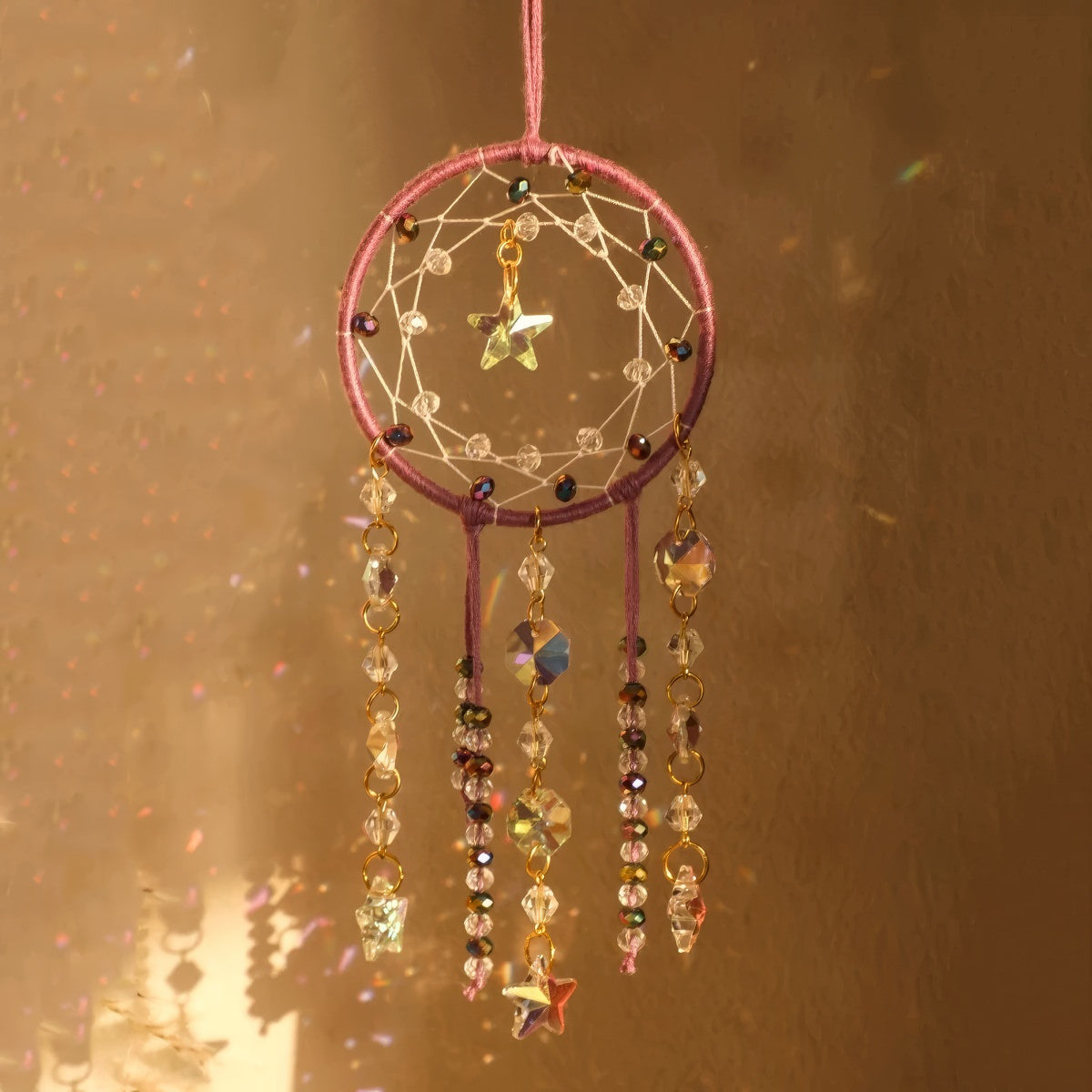Crystal dreamcatcher wall hanging with prism beads, star charms, and sun-catching crystal strands in ivory and pink designs.