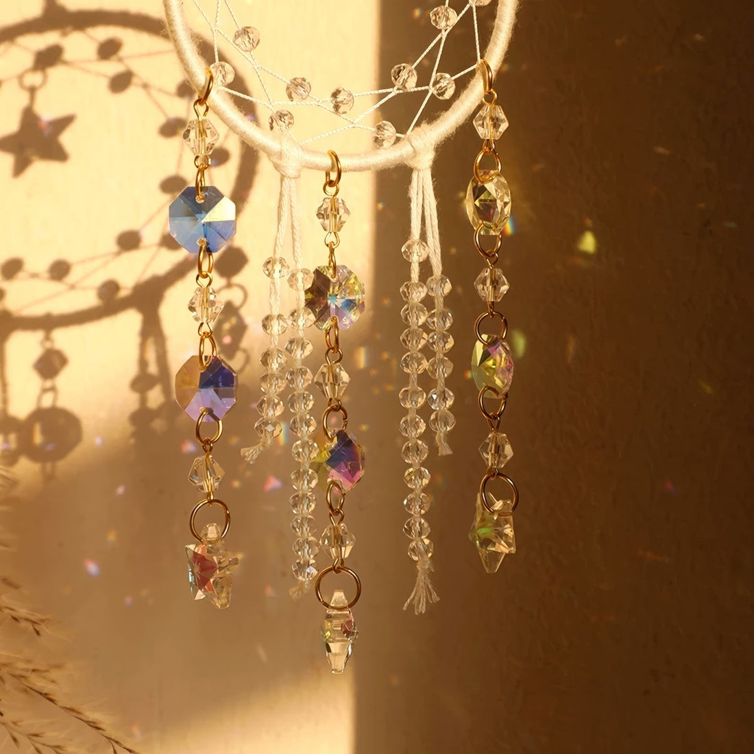 Crystal dreamcatcher wall hanging with prism beads, star charms, and sun-catching crystal strands in ivory and pink designs.