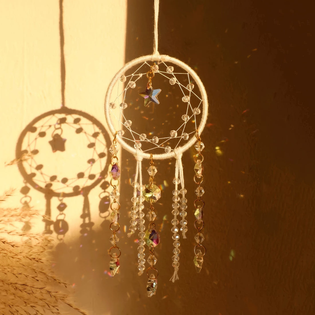 Crystal dreamcatcher wall hanging with prism beads, star charms, and sun-catching crystal strands in ivory and pink designs.