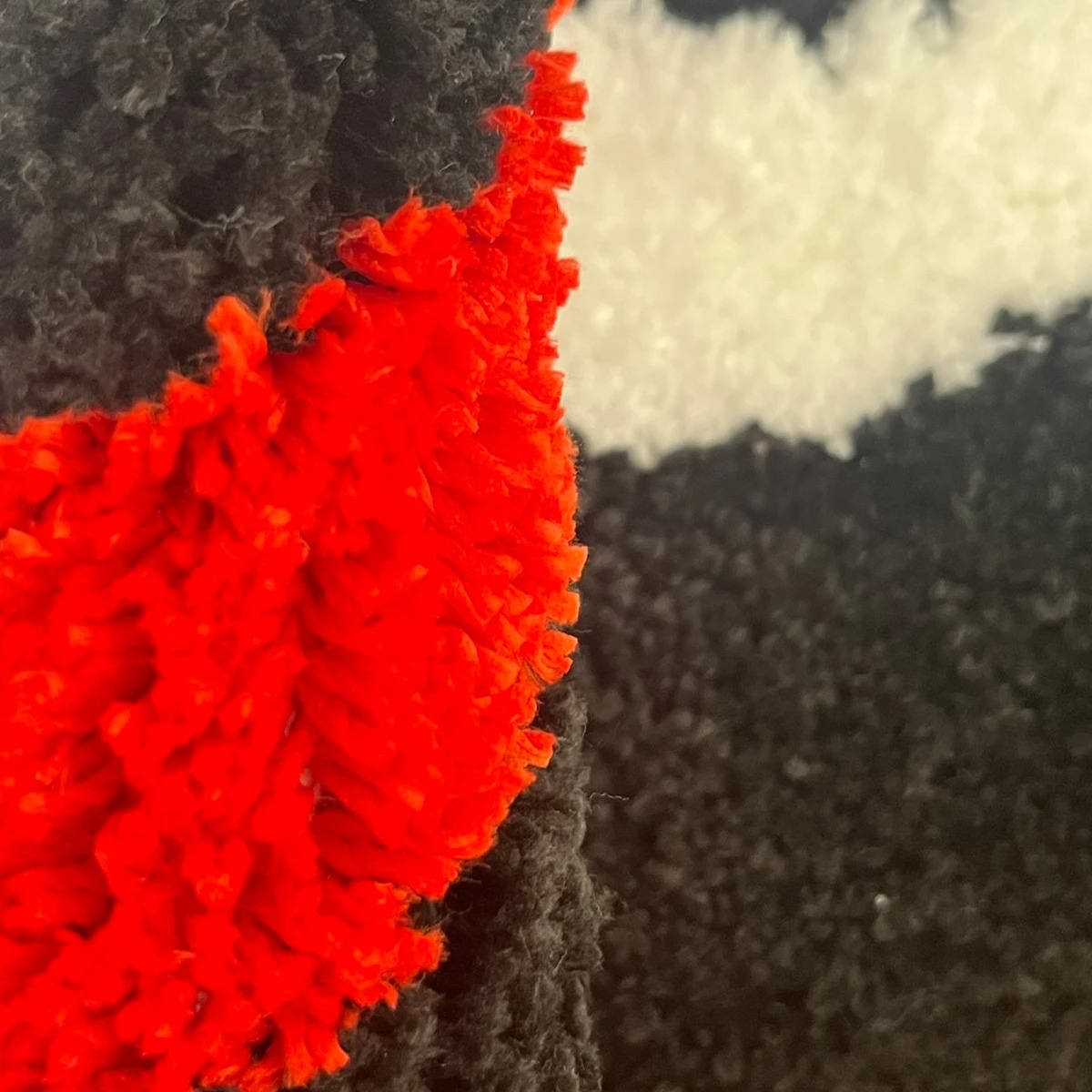 Round tufted rug with a black eight-ball design and red-yellow flame pattern.