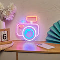camera-shaped wall neon sign with pastel pink and blue glowing