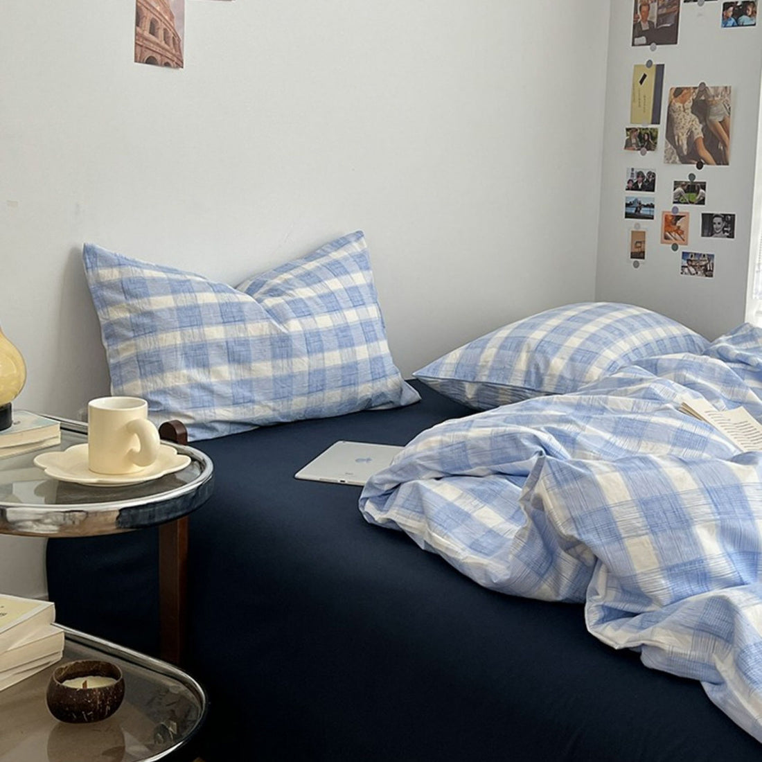 Minimalist bedroom with soft blue and white gingham duvet cover set and matching pillowcases on a dark fitted sheet.