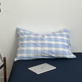 Minimalist bedroom with soft blue and white gingham duvet cover set and matching pillowcases on a dark fitted sheet.