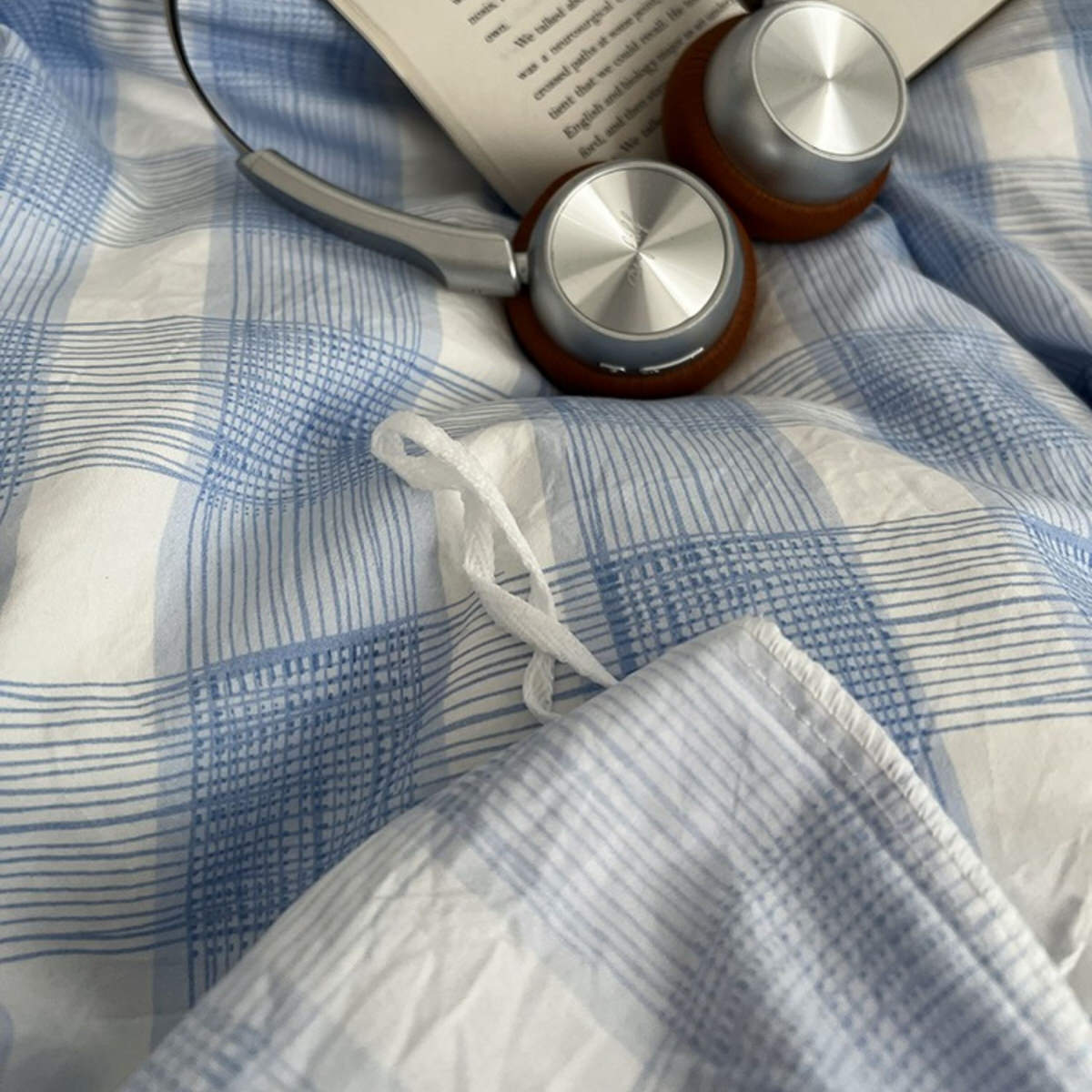 Minimalist bedroom with soft blue and white gingham duvet cover set and matching pillowcases on a dark fitted sheet.