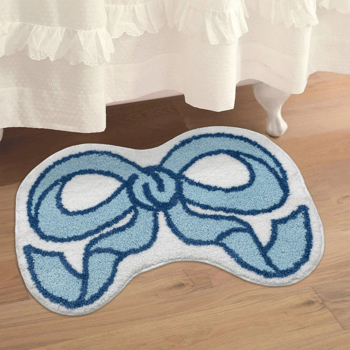 Blue and white bow-shaped rug on a wooden floor with a white curtain in the background.