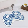 Bath mat with blue bow design on a bathroom floor