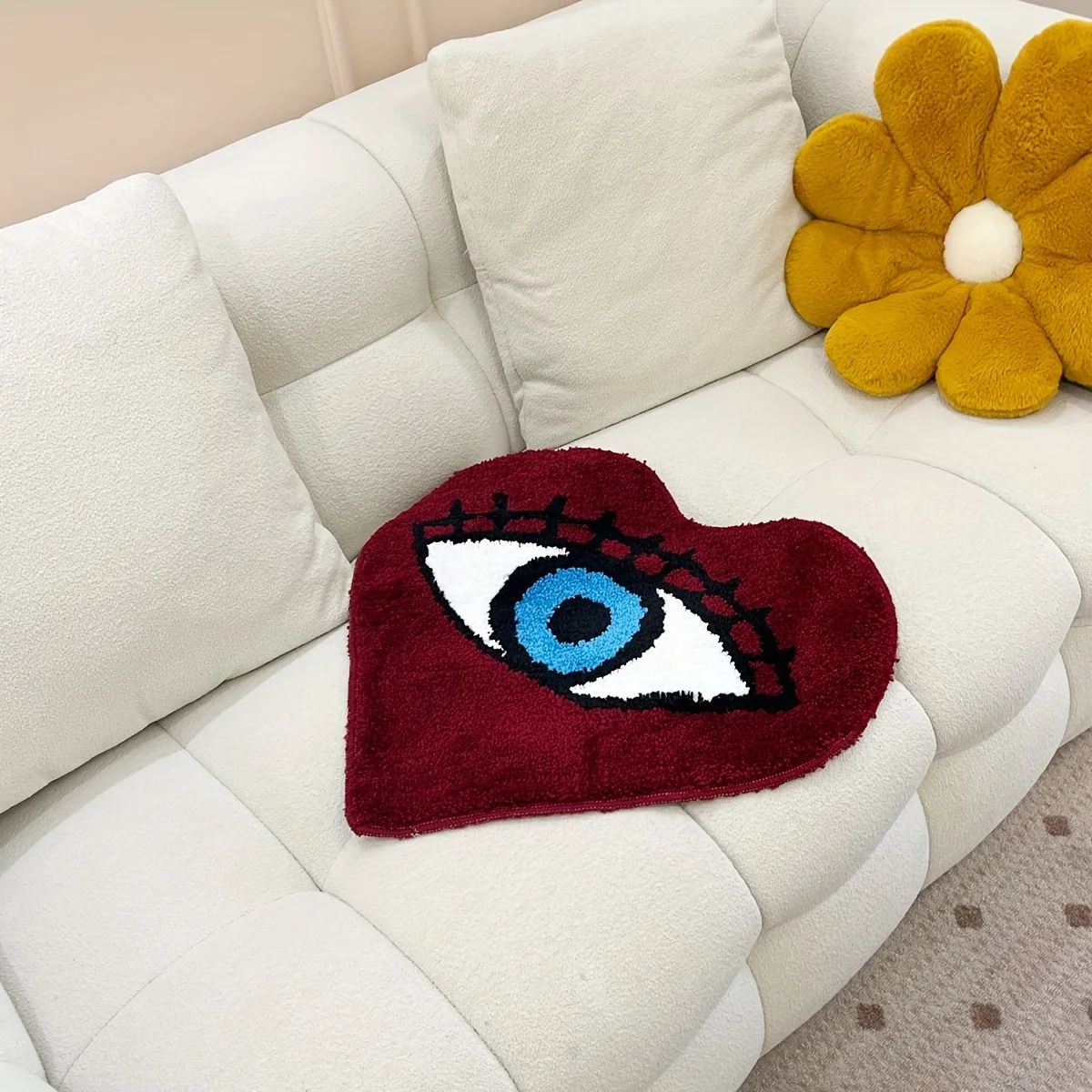 Heart-shaped dark red tufted rug with a large blue evil eye design and black lashes