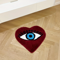 Heart-shaped dark red tufted rug with a large blue evil eye design and black lashes