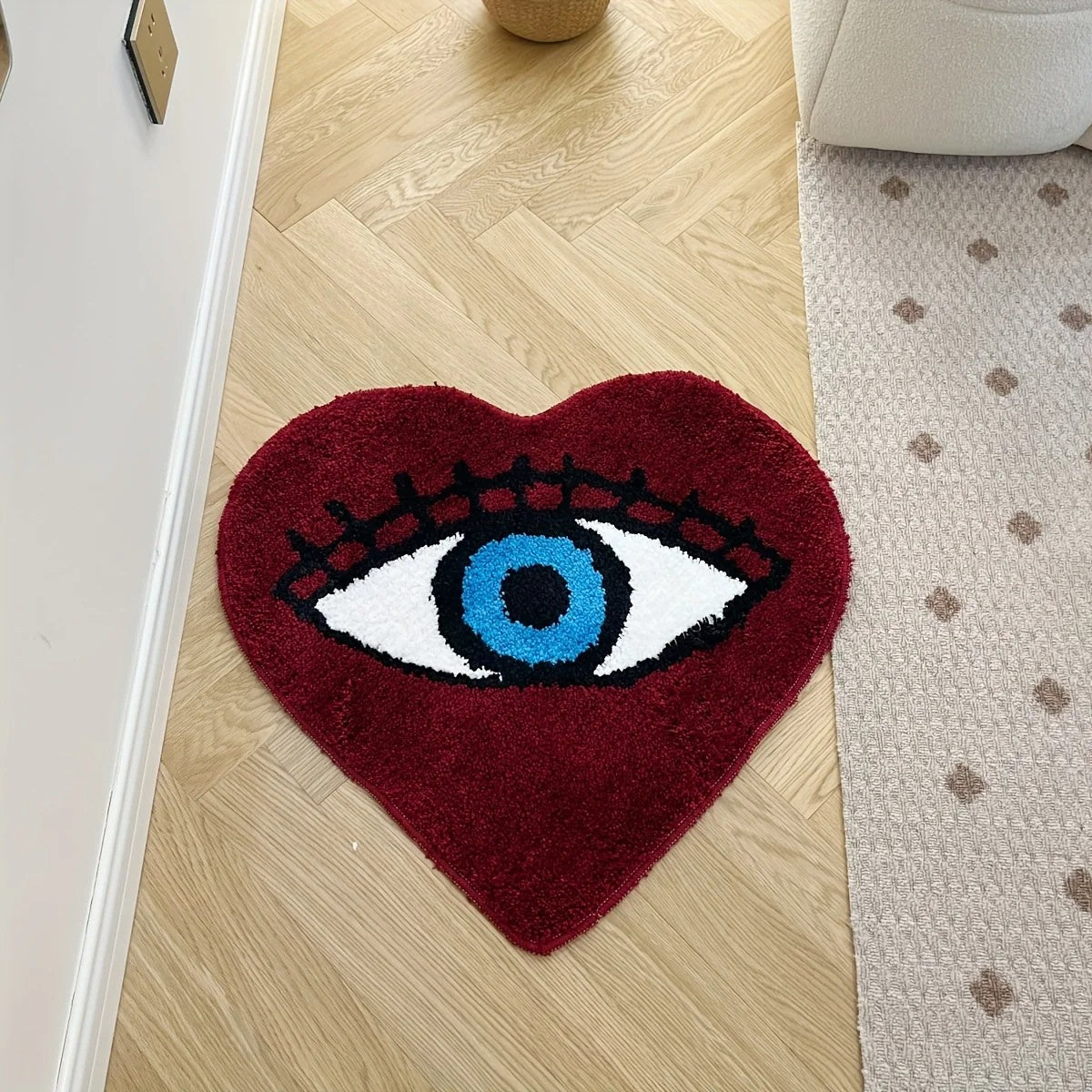 Heart-shaped dark red tufted rug with a large blue evil eye design and black lashes