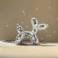 Small mirrored balloon dog decorative sculpture in silver and pink mosaic finish reflecting sunlight on a tabletop.