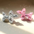 Small mirrored balloon dog decorative sculpture in silver and pink mosaic finish reflecting sunlight on a tabletop.