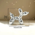 Small mirrored balloon dog decorative sculpture in silver and pink mosaic finish reflecting sunlight on a tabletop.