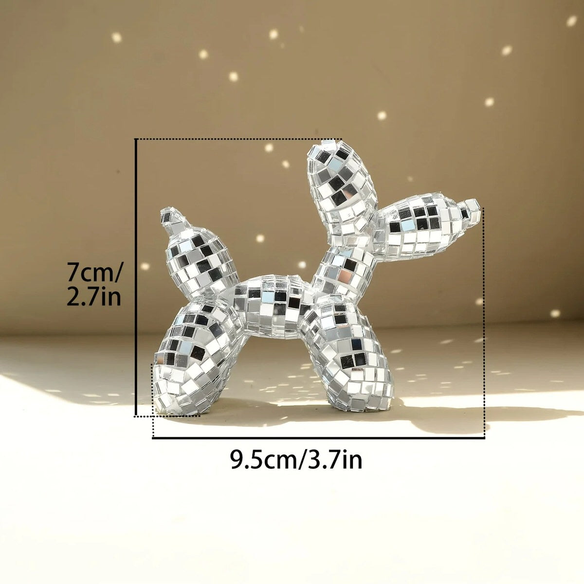 Small mirrored balloon dog decorative sculpture in silver and pink mosaic finish reflecting sunlight on a tabletop.