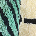 Tufted area rug designed as a stack of green dollar cash bills with a cream paper band