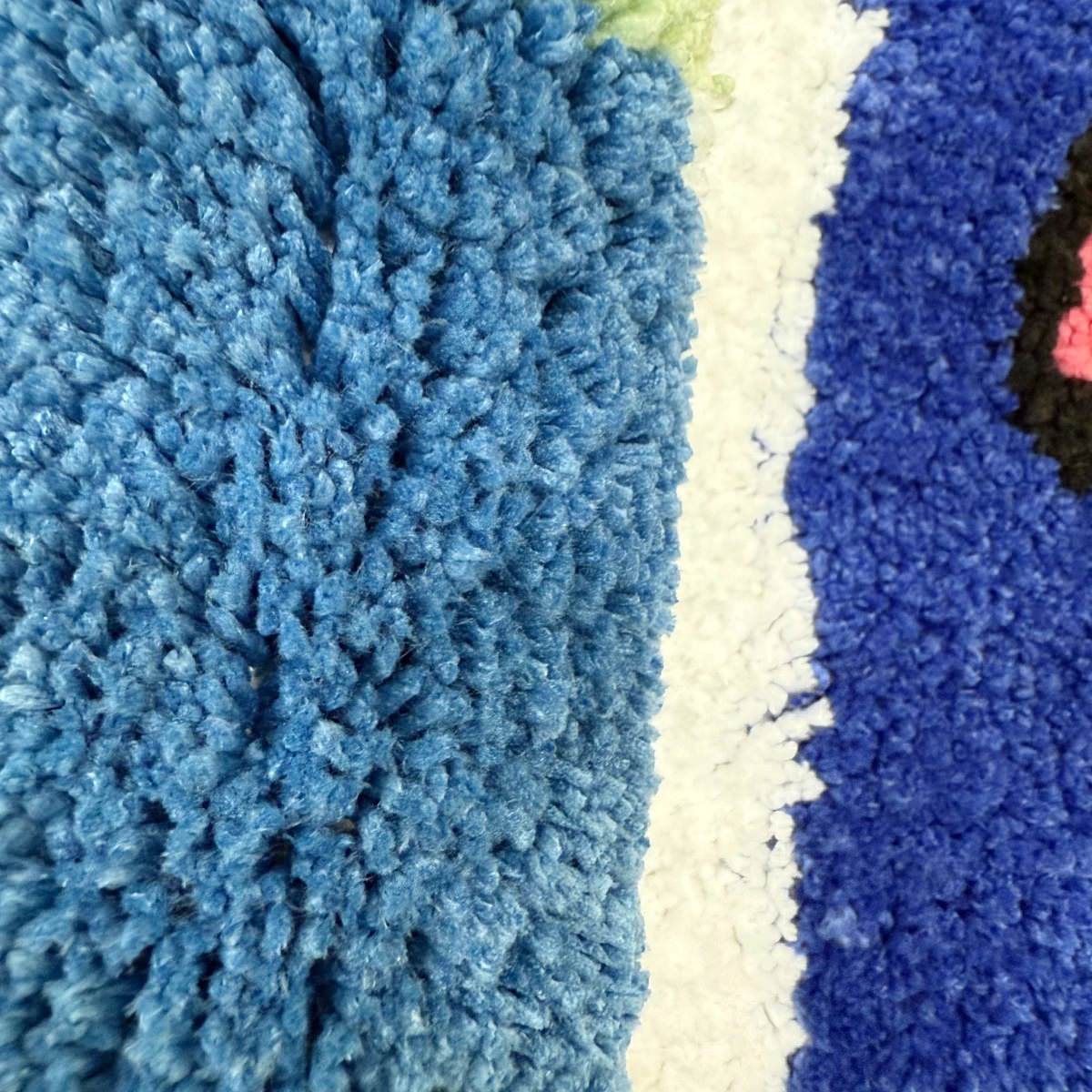 A tufted rug shaped like an arched window, displaying a blue sky with white clouds and a colorful bird on the sill