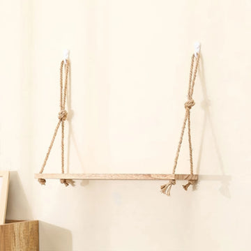A rustic wooden shelf suspended by two thick natural-fiber rope hangers with knots