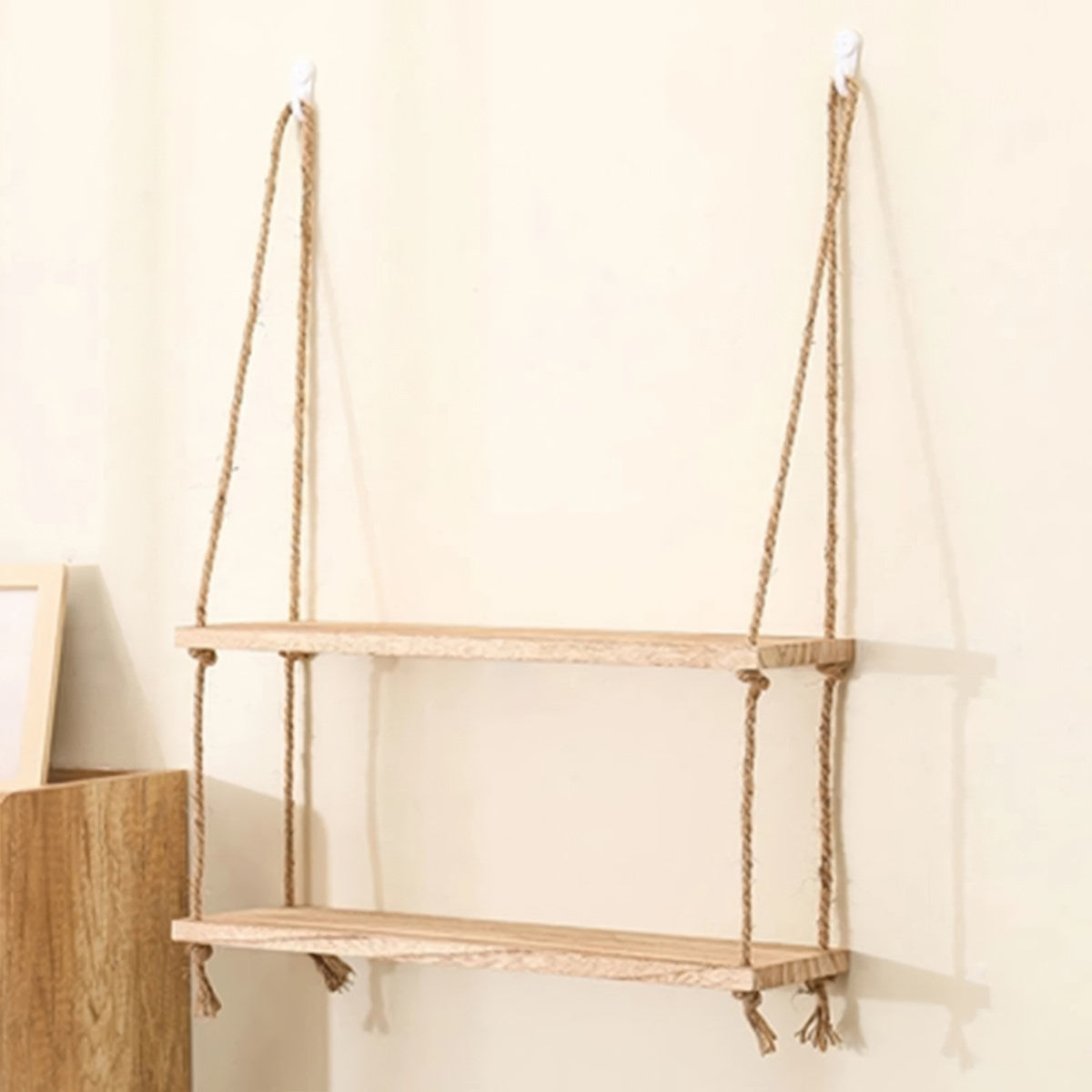 A rustic wooden shelf suspended by two thick natural-fiber rope hangers with knots