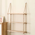 A rustic wooden shelf suspended by two thick natural-fiber rope hangers with knots