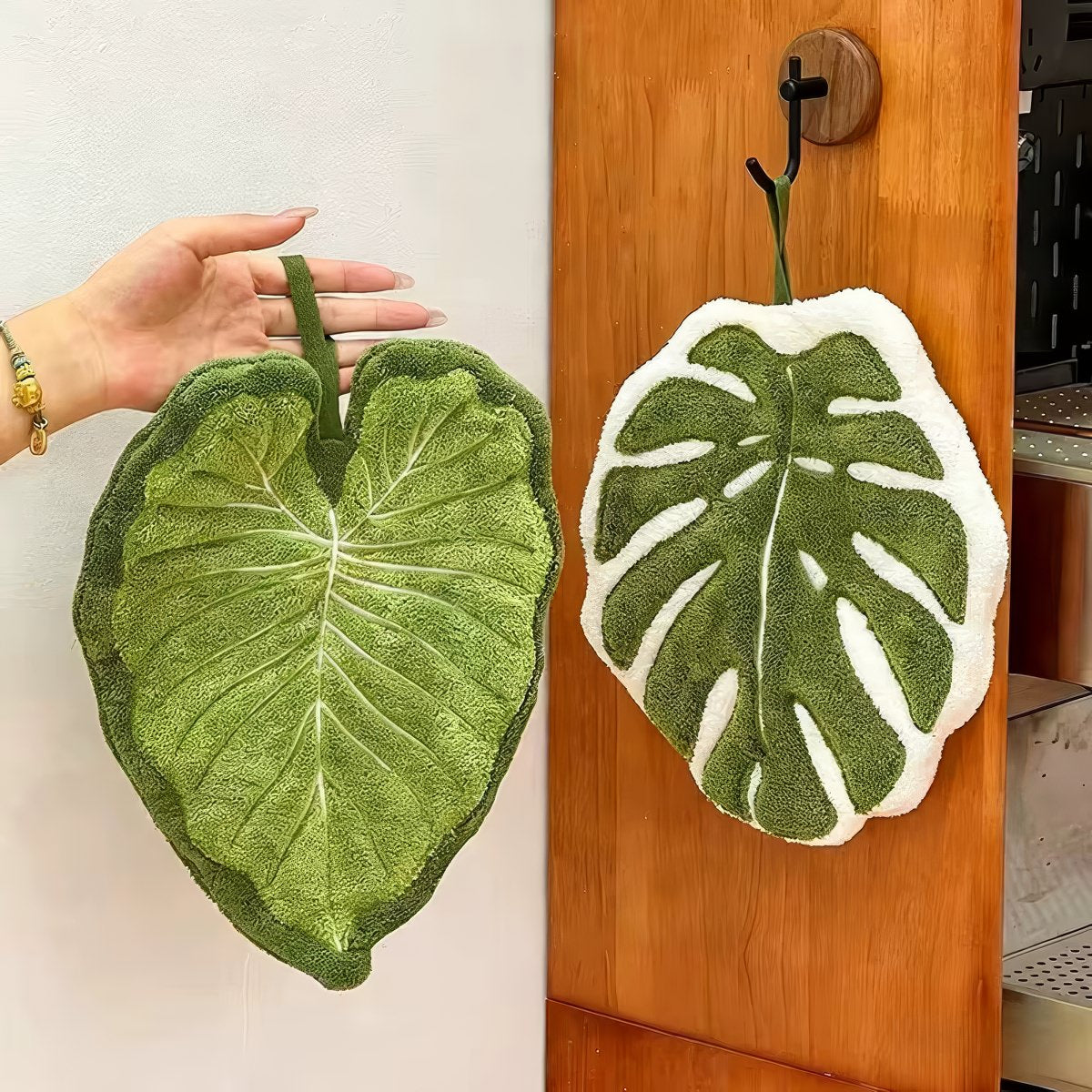 Leaf-shaped tufted hanging hand towel in green botanical designs with textured veins and hanging loop, shown in multiple tropical leaf styles and sizes.