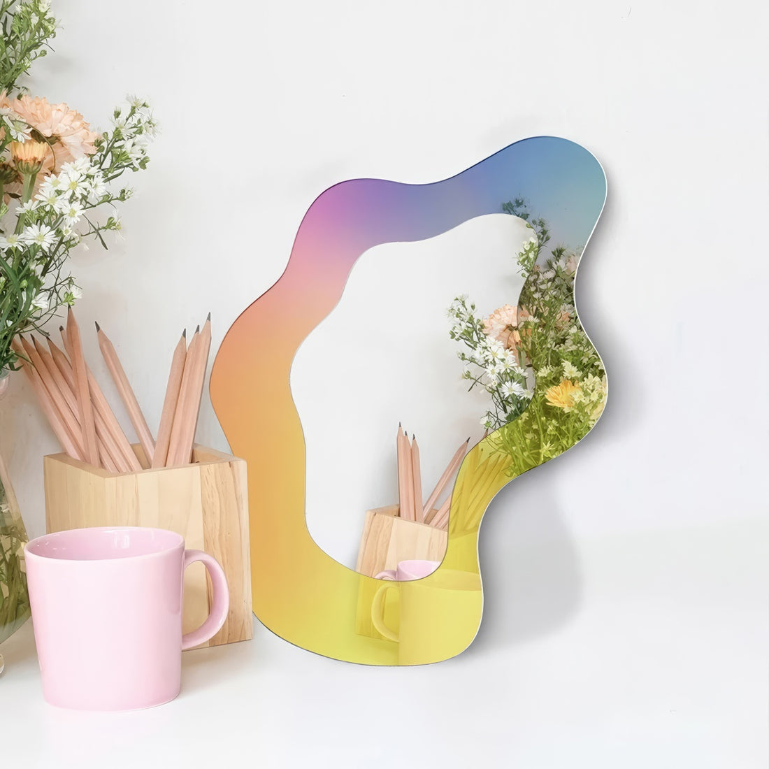 An abstract, wavy-edged acrylic mirror with a holographic iridescent finish that shifts between pink, purple, and light blue
