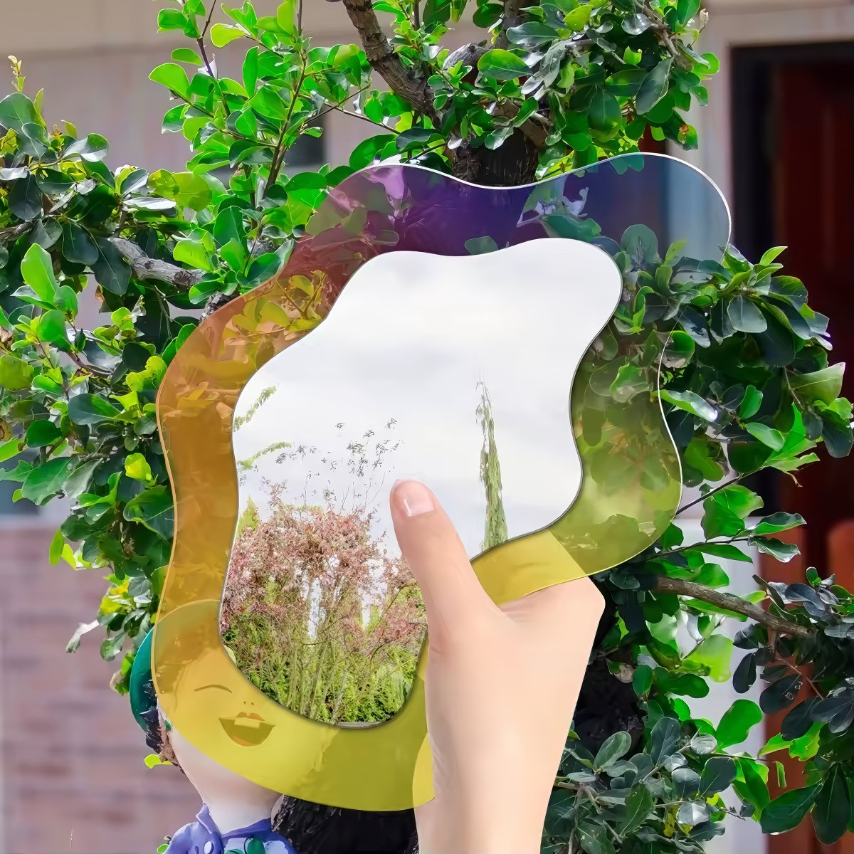 An abstract, wavy-edged acrylic mirror with a holographic iridescent finish that shifts between pink, purple, and light blue