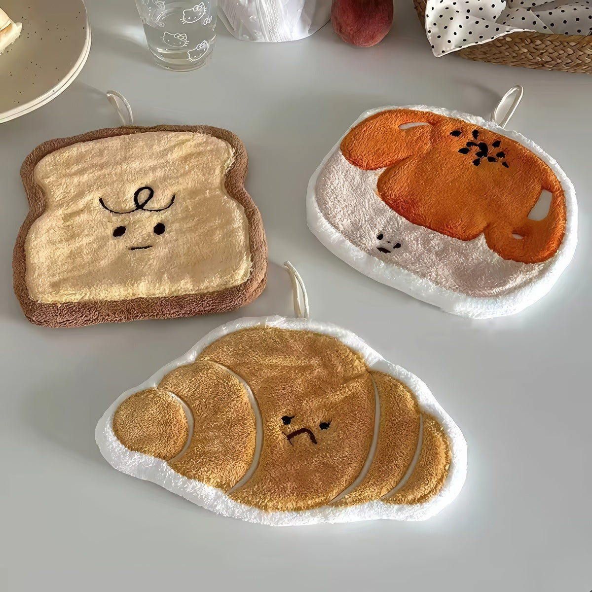 Plush kawaii hanging hand towel shaped like bread, croissant, toast, egg toast, and garlic with embroidered faces and hanging loops.