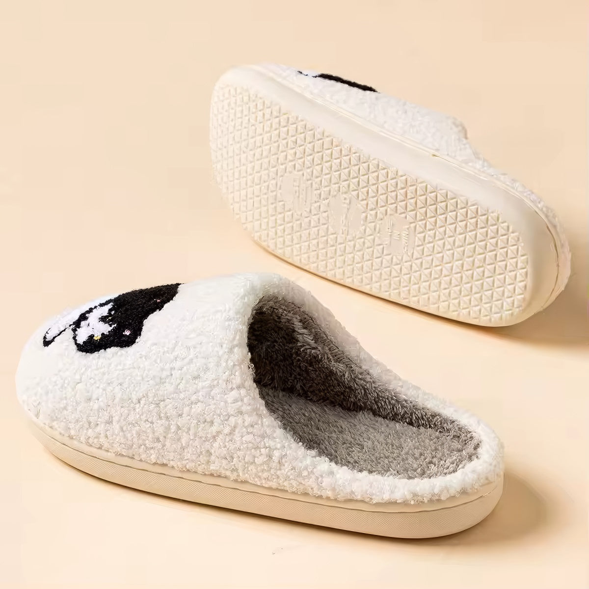 Pair of white plushie slippers with a black and white cat design