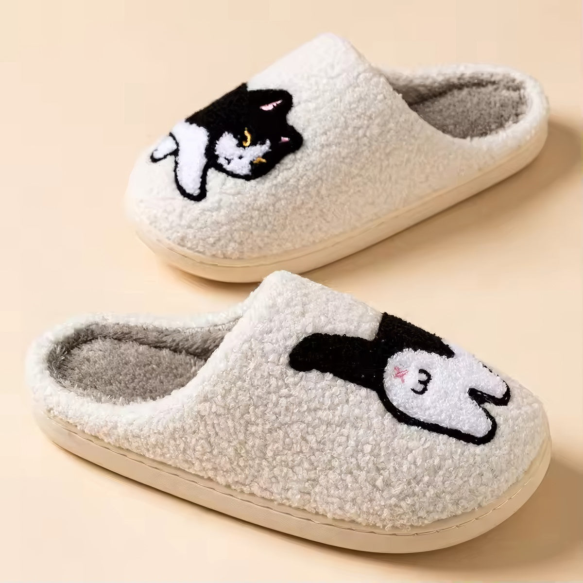 Pair of white plushie slippers with a black and white cat design