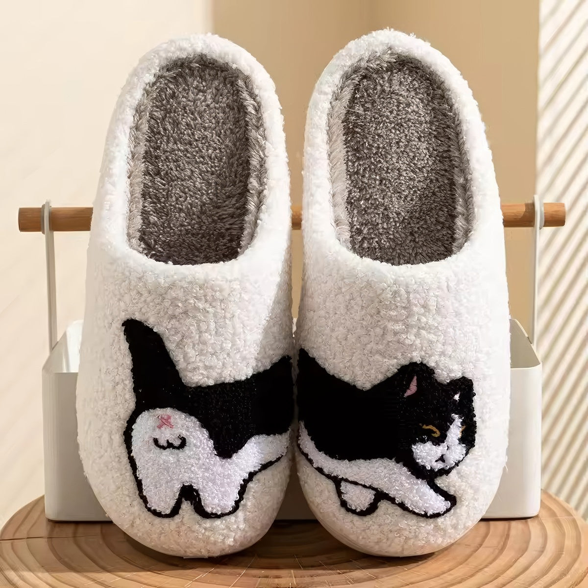 Pair of white plushie slippers with a black and white cat design