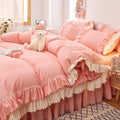 Pink ruffled bedding set with white frill trim, including a duvet cover, pillowcases, and bed skirt, in a soft and feminine coquette aesthetic